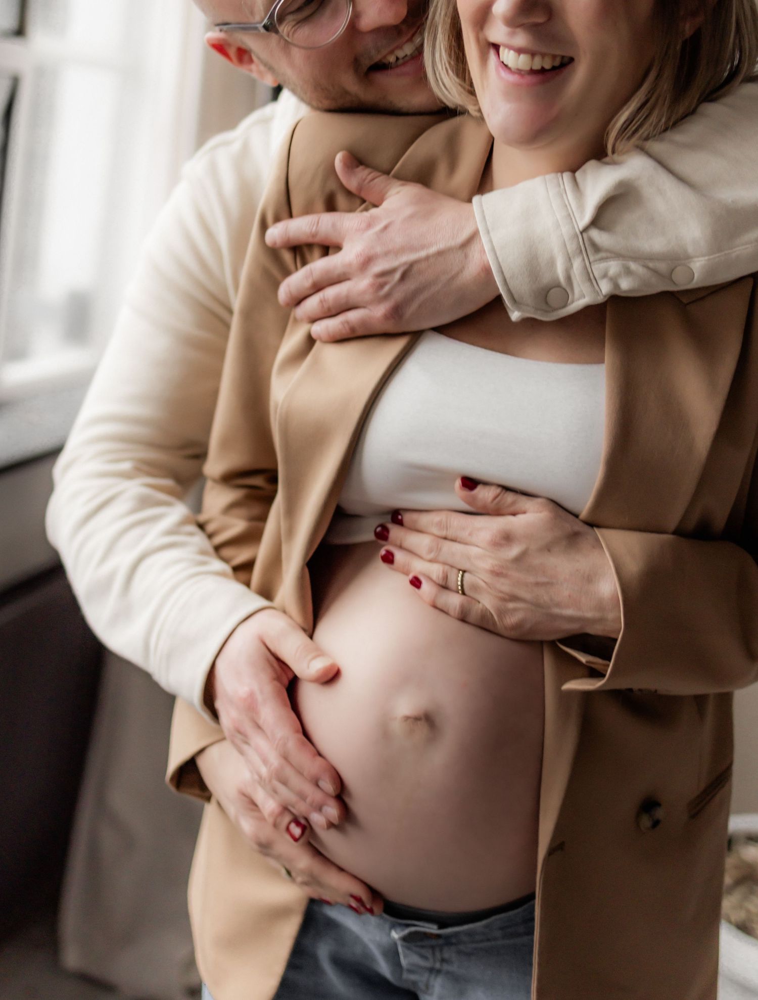 Intimate maternity photos showing hands cradling pregnant belly in natural light.