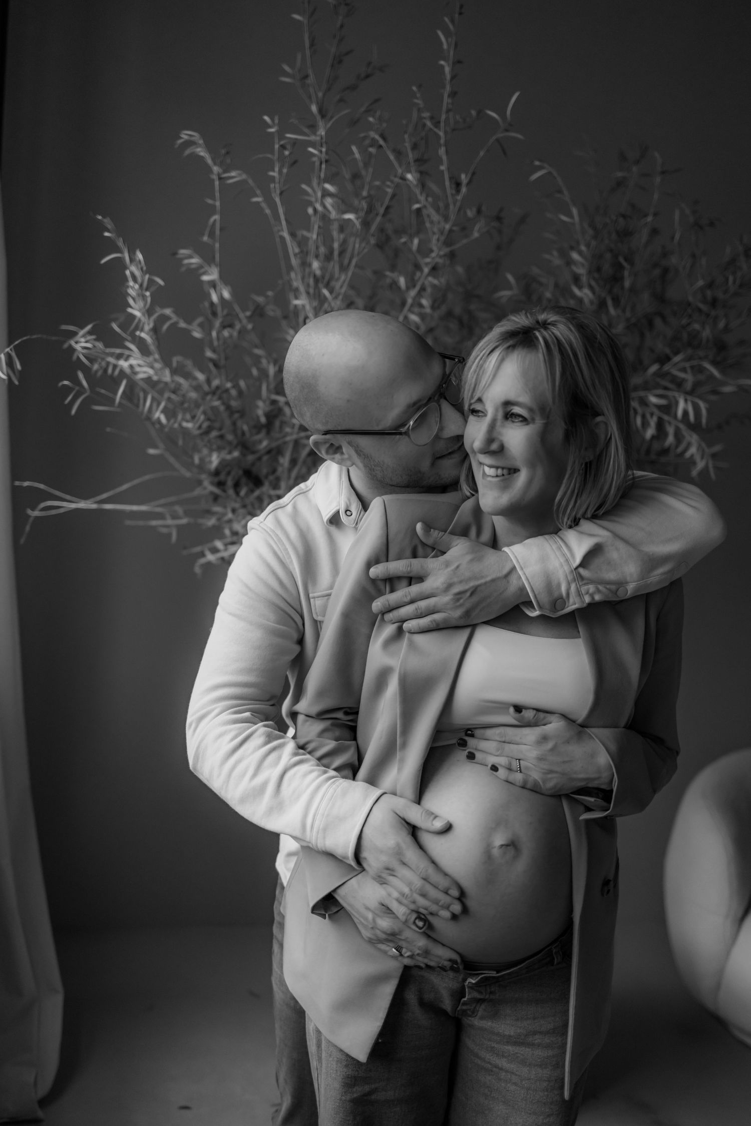 Black and white maternity series with decorative branches and emotional moments.