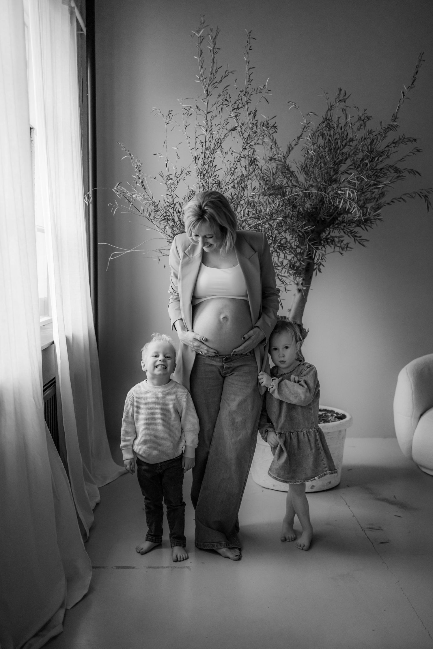 Black and white family portrait showing small children and an adult figure by a window.