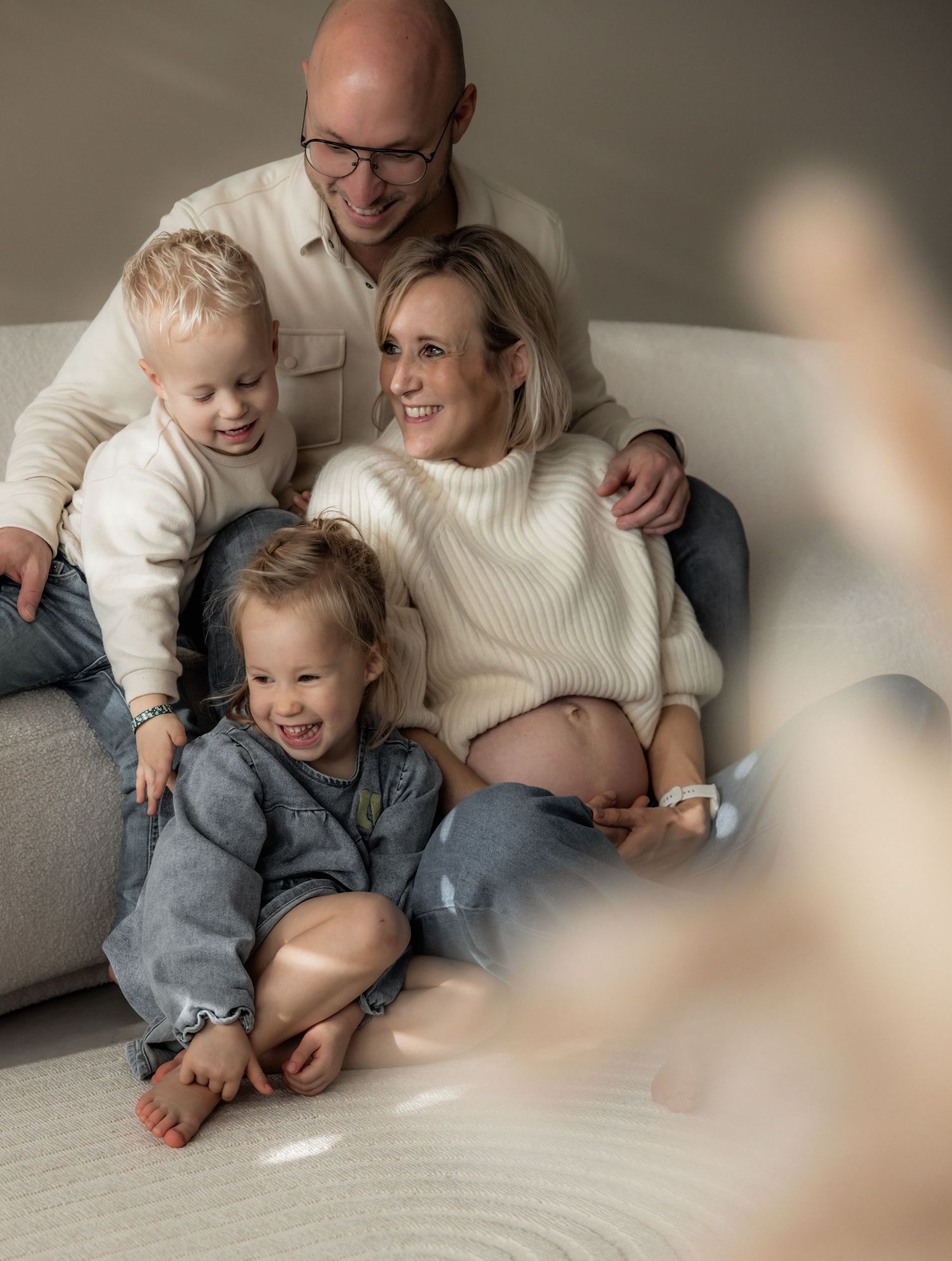 Candid family moment captured on a light carpet showing playful interaction and laughter.