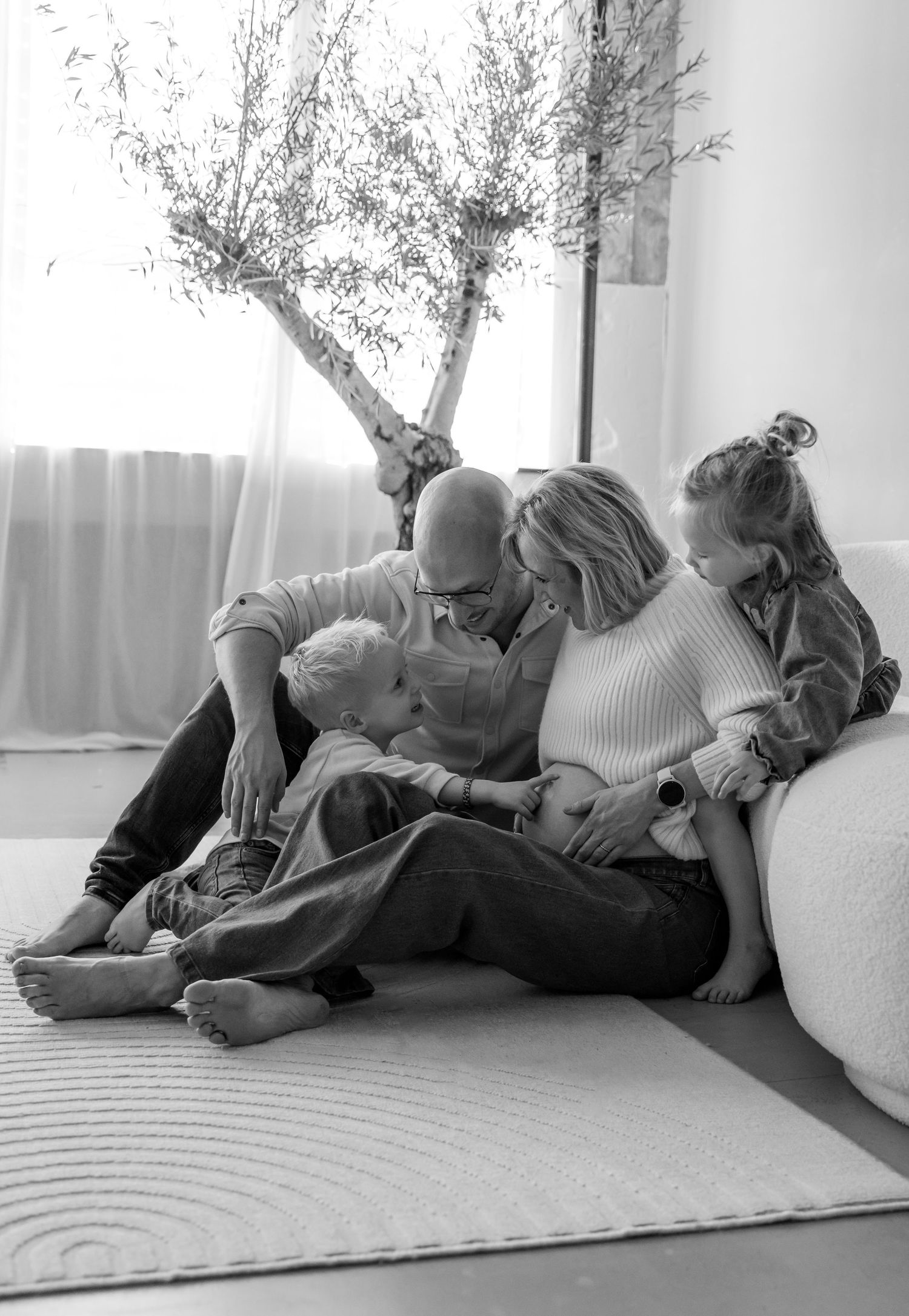Series of black and white photos showing intimate family moments on a carpeted floor.