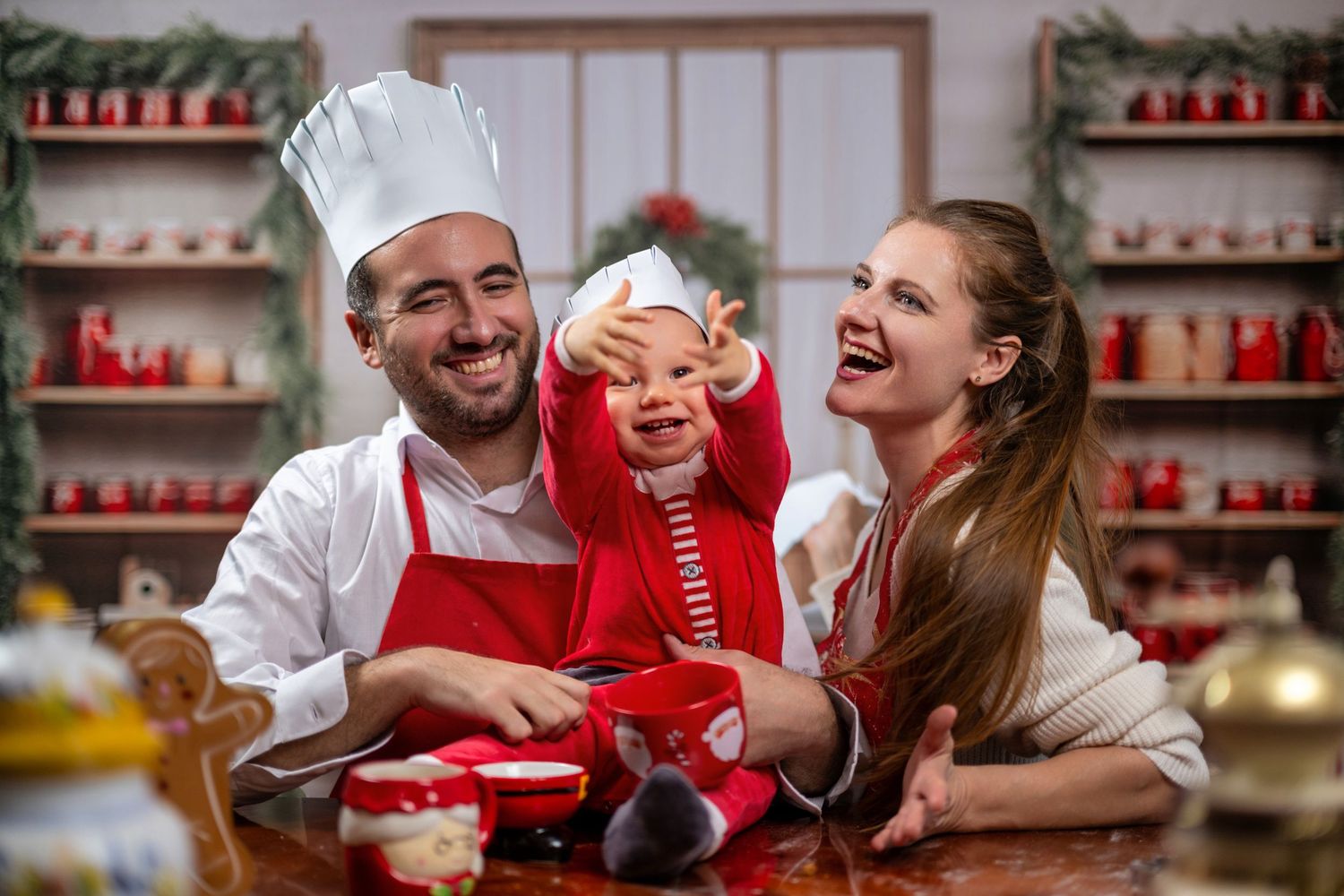People enjoying hot beverages and sweet treats together in a cozy red-decorated holiday kitchen setting.