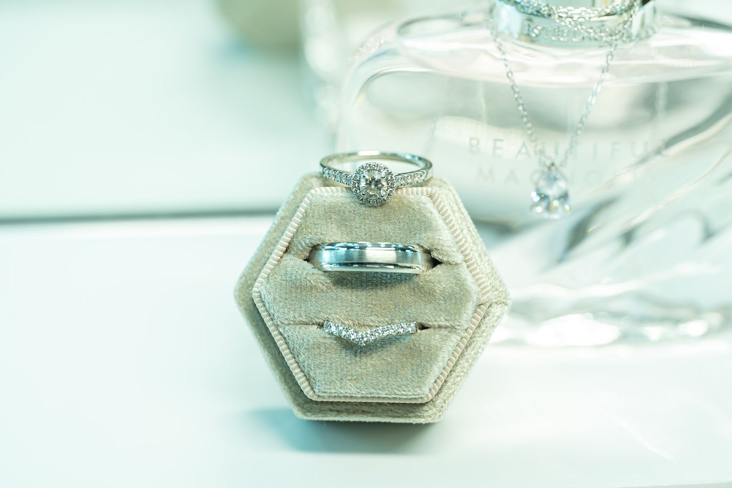 Multiple engagement rings with diamonds set in hexagonal bezels displayed on reflective surfaces.