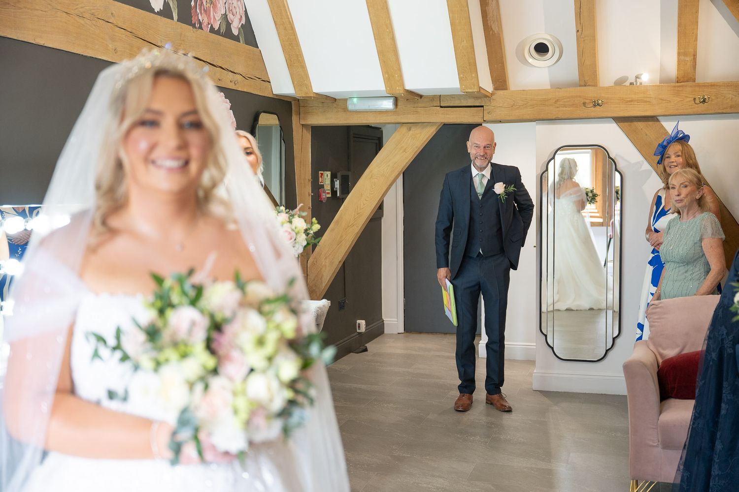 Wedding party poses in elegant rustic venue with exposed wooden beams and natural lighting.