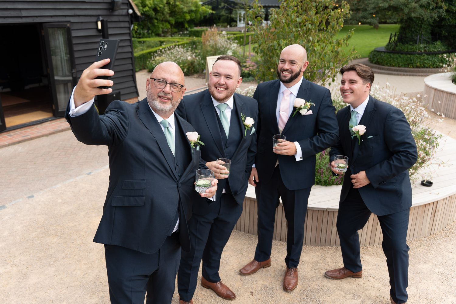 Groomsmen in navy suits pose playfully on stone steps during an outdoor wedding photo session.