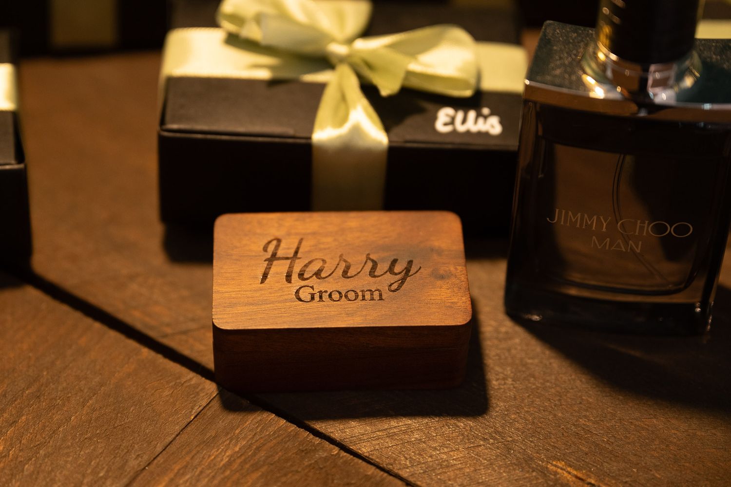 Wedding name place cards and table decor arranged on a dark wooden surface in warm lighting.