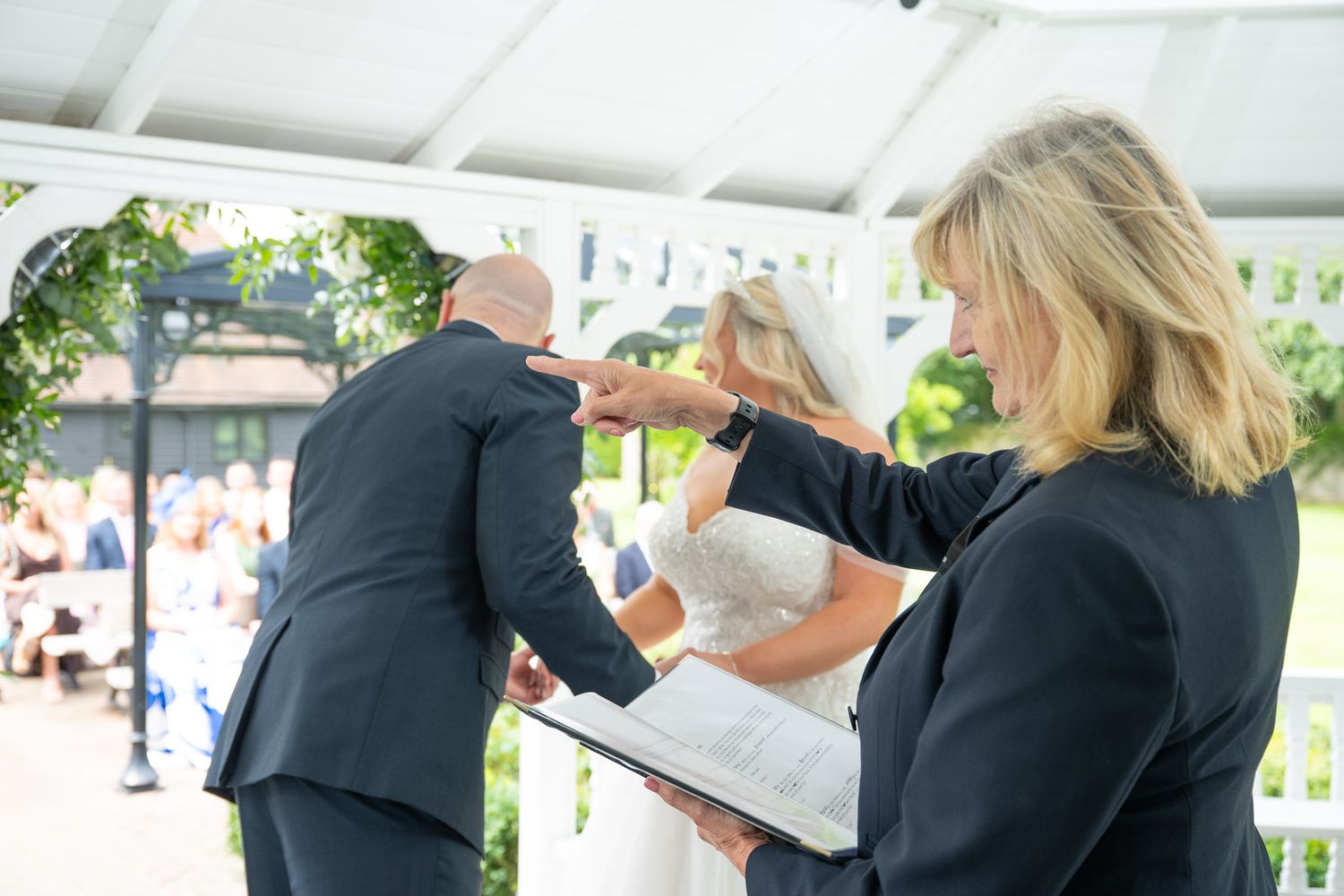 A group stands together under a white pavilion during a daytime gathering.