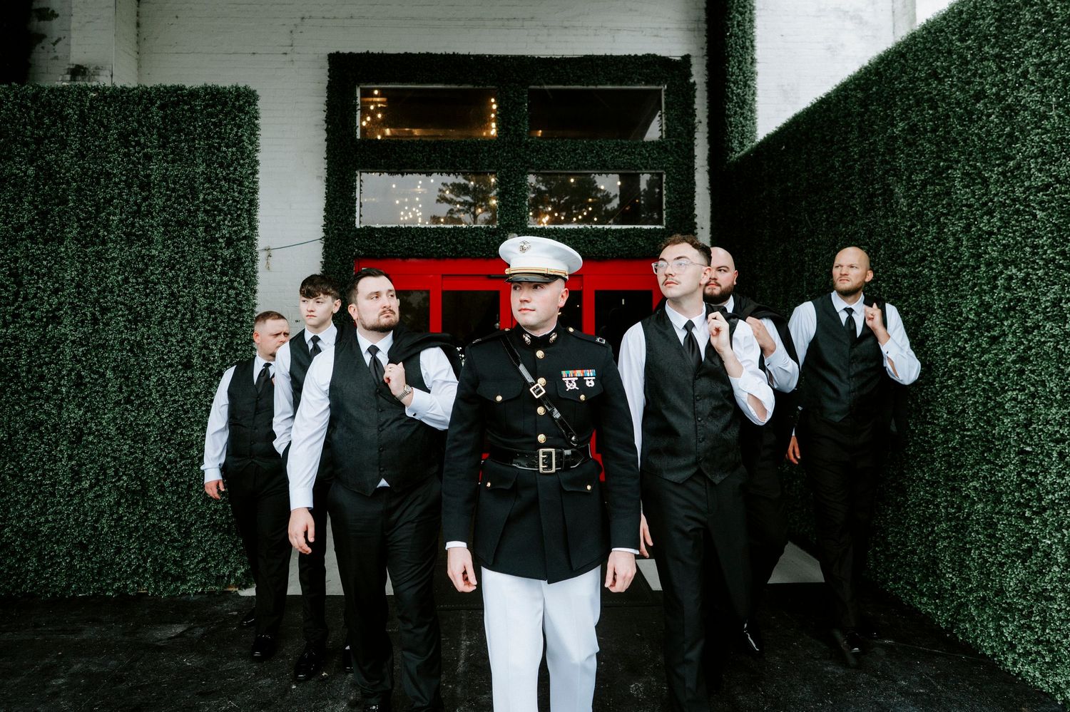A group of people in formal black and white attire walk through a dark corridor.