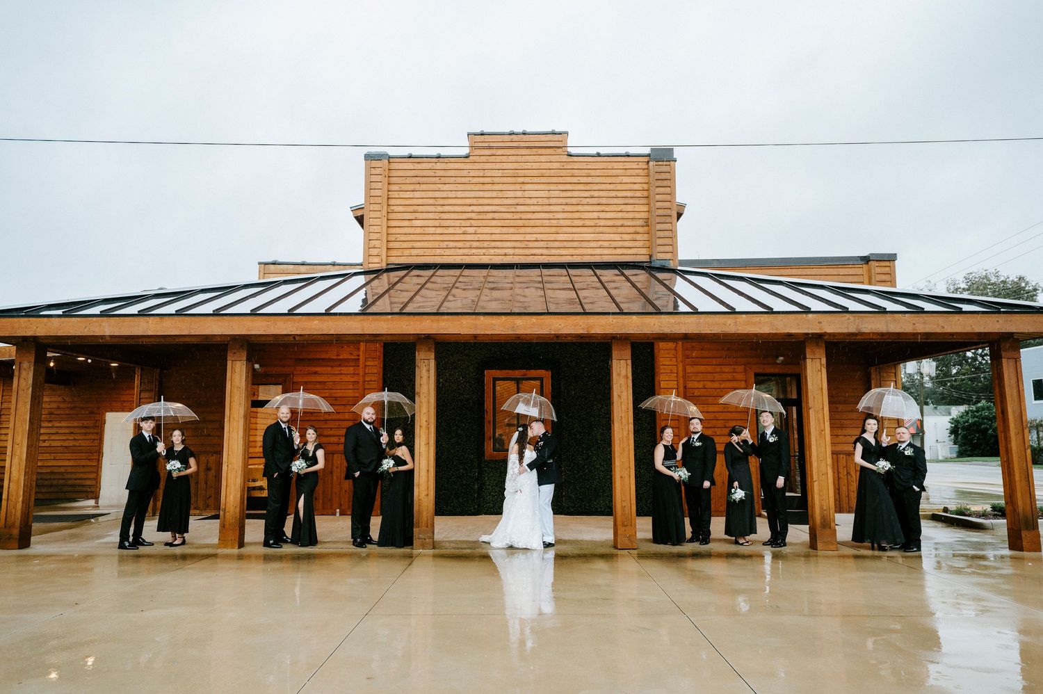 Modern wedding venue exterior featuring a long covered porch with wooden columns and metal roof.