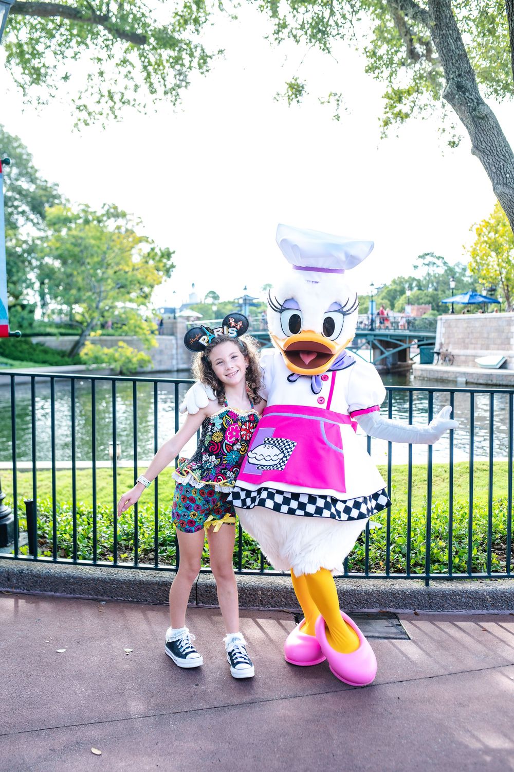 Four sequential photos show a playful interaction with a costumed character in a pink and white outfit at a theme park.
