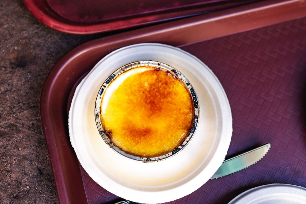 A series of white plates with creme brulee desserts showing different stages of caramelization and preparation.
