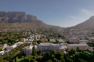 Panoramic view of Table Mountain and surrounding cityscape of Cape Town, South Africa under blue skies.