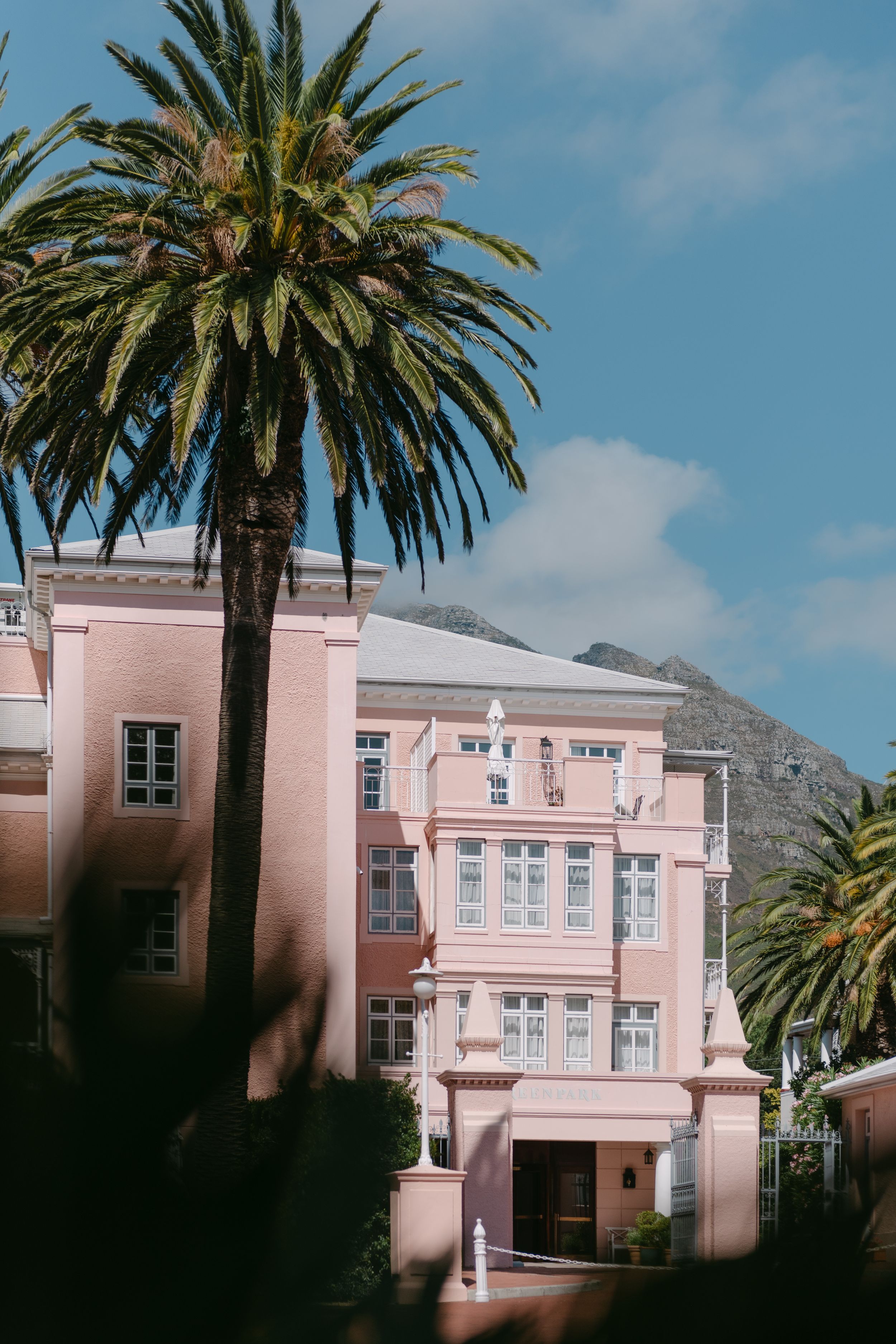 A pink colonial-style building with palm trees and blue sky in Cape Town, South Africa.