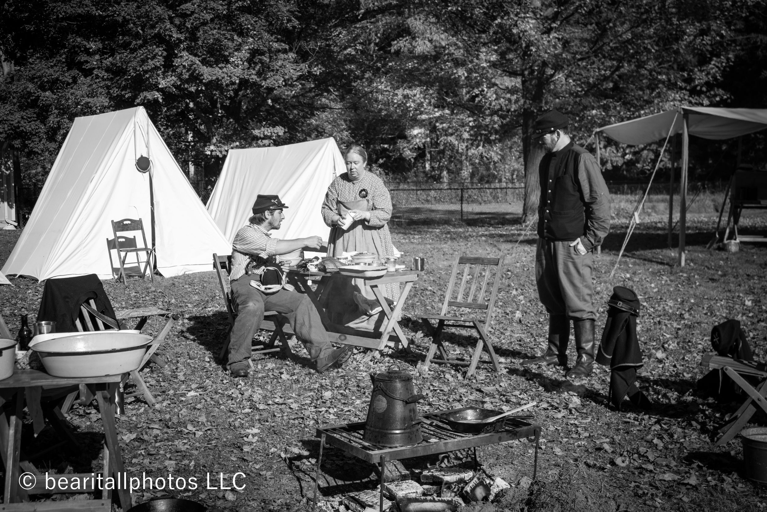 Historical reenactment camp with white canvas tents set up in a field during autumn.