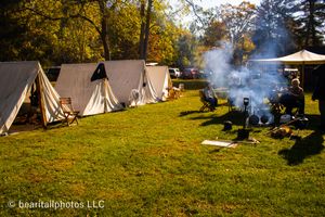 White canvas tents line a grassy field during an autumn Civil War reenactment event.