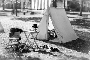 Civil War era camp setup with tents and period equipment in black and white photograph.