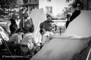 Historical reenactment camp showing participants gathered around canvas tents.