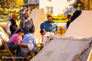 Historical reenactment participants gathered at a campsite with period-accurate tents.
