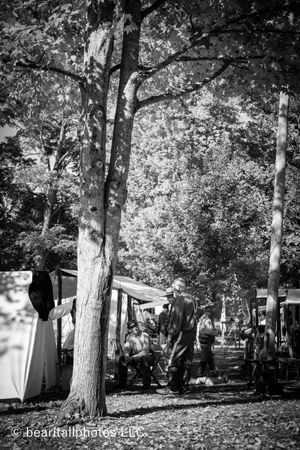 Black and white photograph of a Civil War reenactment encampment among tall trees.