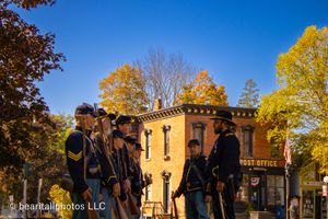 Civil War reenactors in uniform gathered outside a historic building during autumn.