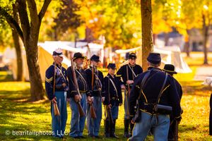 Civil War reenactors gather in a line under golden autumn trees during a historical demonstration.