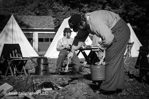 Historical reenactors in period dress gathered around canvas tents during an autumn event.