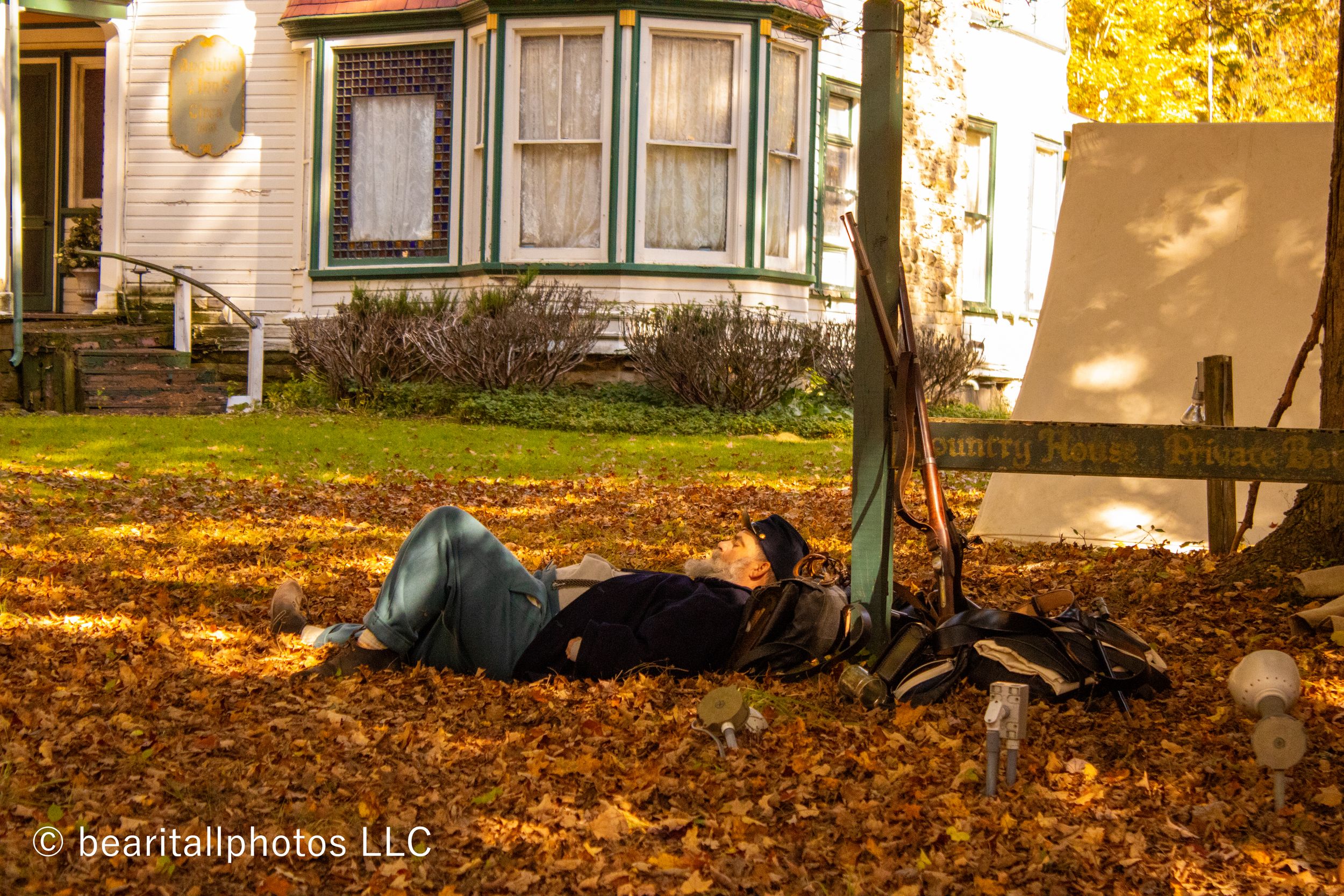 Historic white house with Civil War era encampment and tents spread across the autumn lawn.