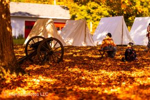 Civil War reenactment camp with tents and equipment illuminated by warm autumn sunlight.