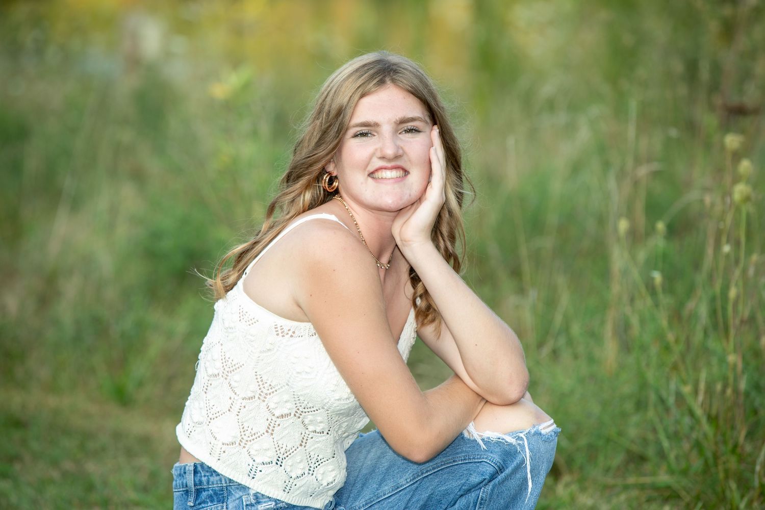 A series of outdoor portrait photos showing someone in a white lace top sitting in a grassy field during golden hour.