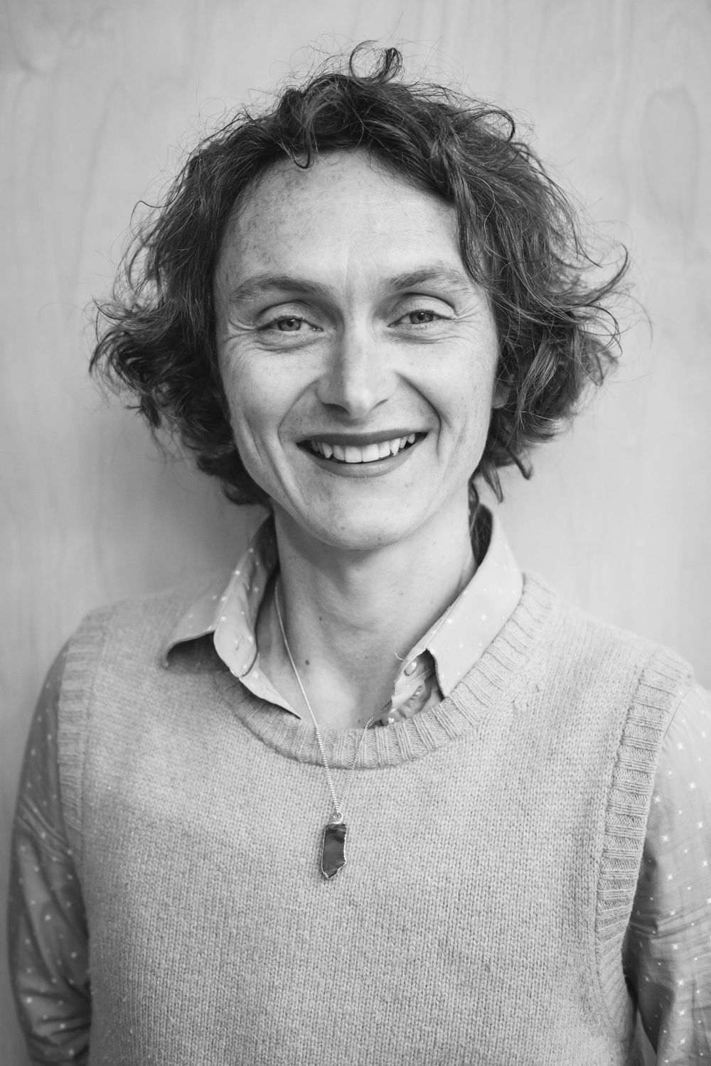 A series of black and white photos showing a person in a sweater with curly hair expressing joyful emotions.