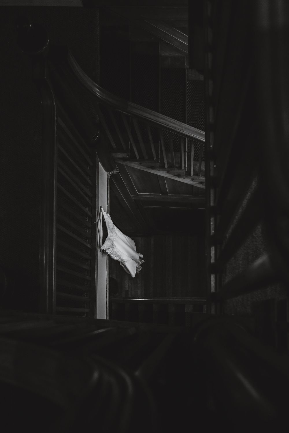 A dark and moody black and white photo shows a white sheet or fabric hanging in a dimly lit interior space.