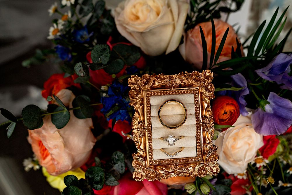 Vintage ornate gold frame surrounded by colorful floral arrangements and wedding decorations.