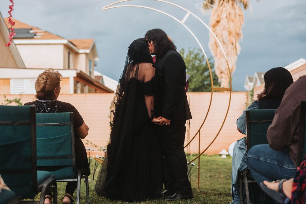 A series of silhouetted figures sit together outdoors at sunset, creating a peaceful social gathering scene.