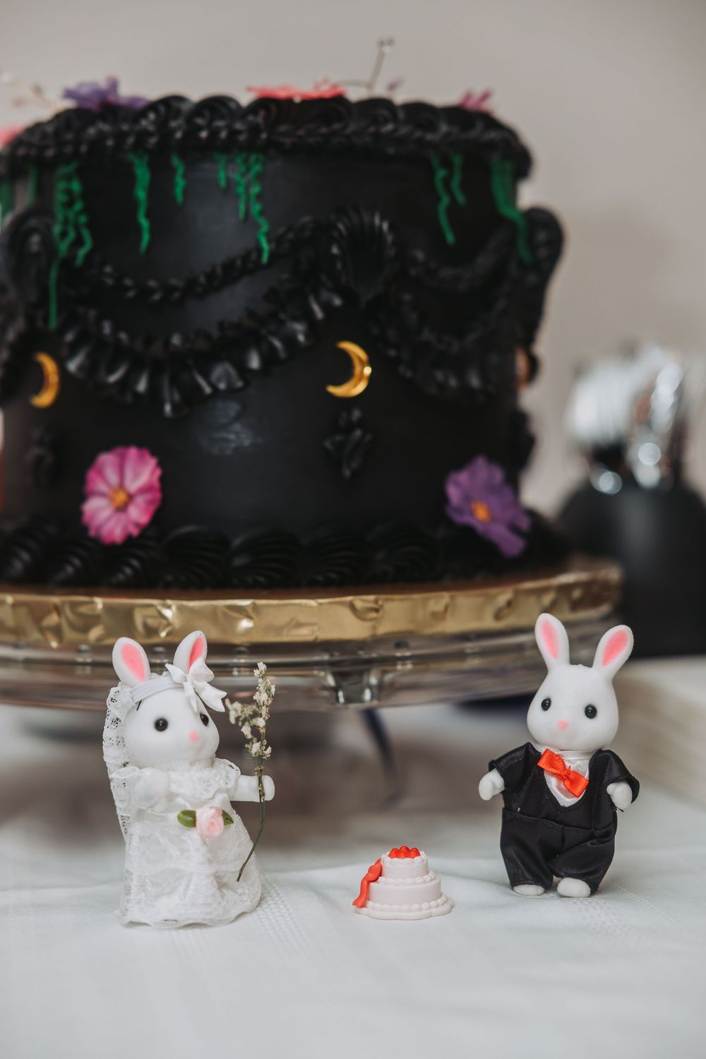 Small plastic mice toys arranged in a row against a black cake base with crescent moon decorations.