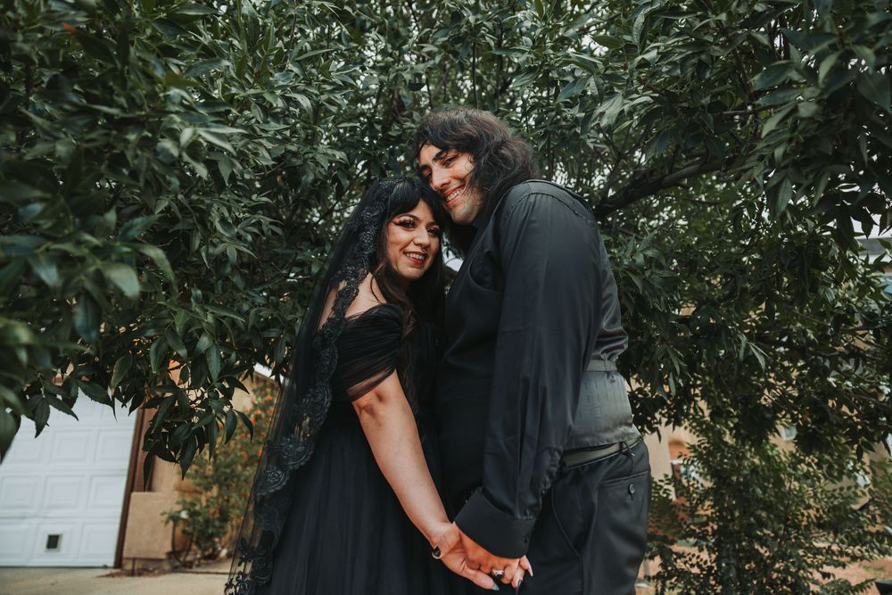 A couple shares an intimate moment in a garden setting surrounded by lush greenery and natural light.