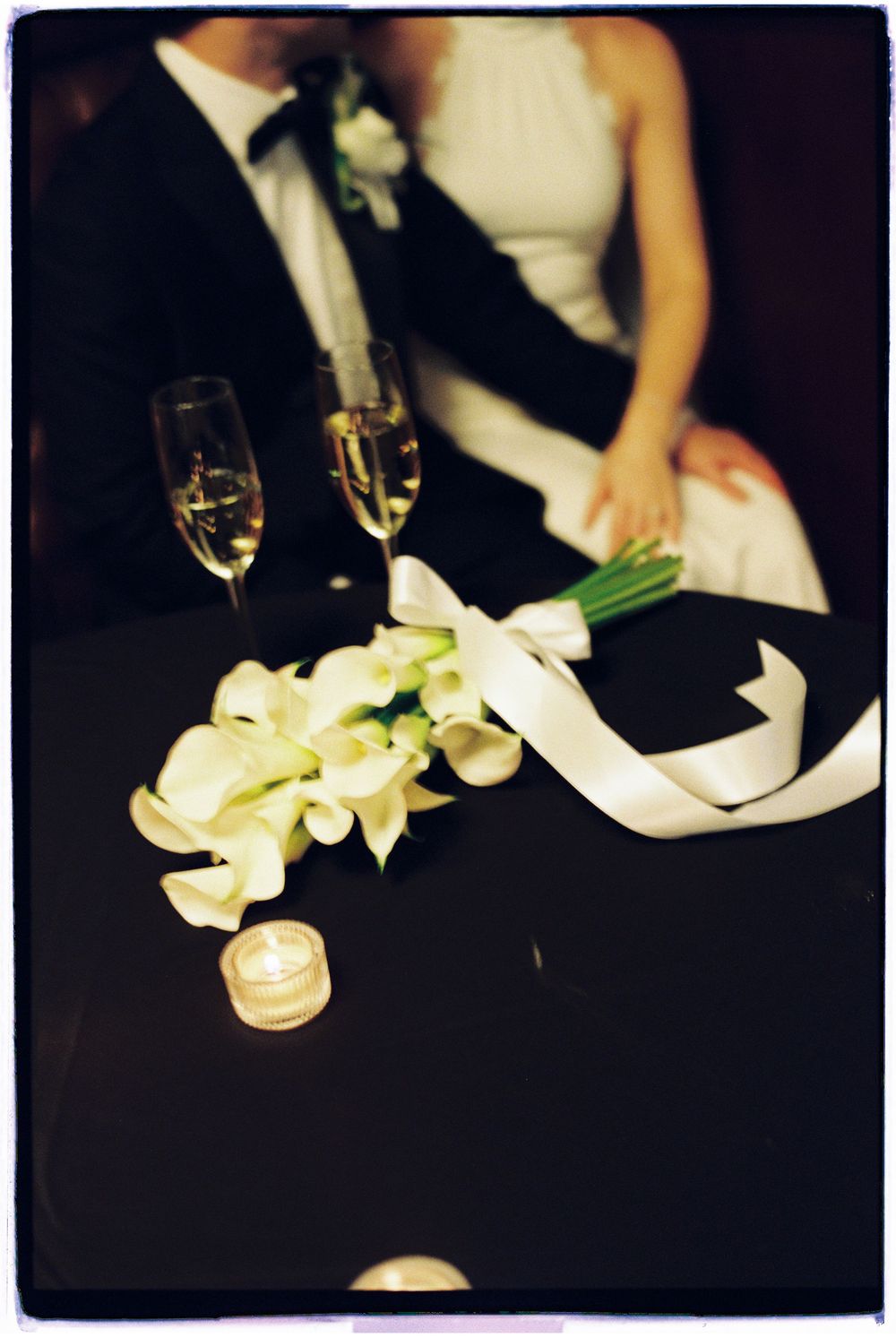 Elegant white orchids and champagne glasses set a romantic mood against a dark background at an upscale event.