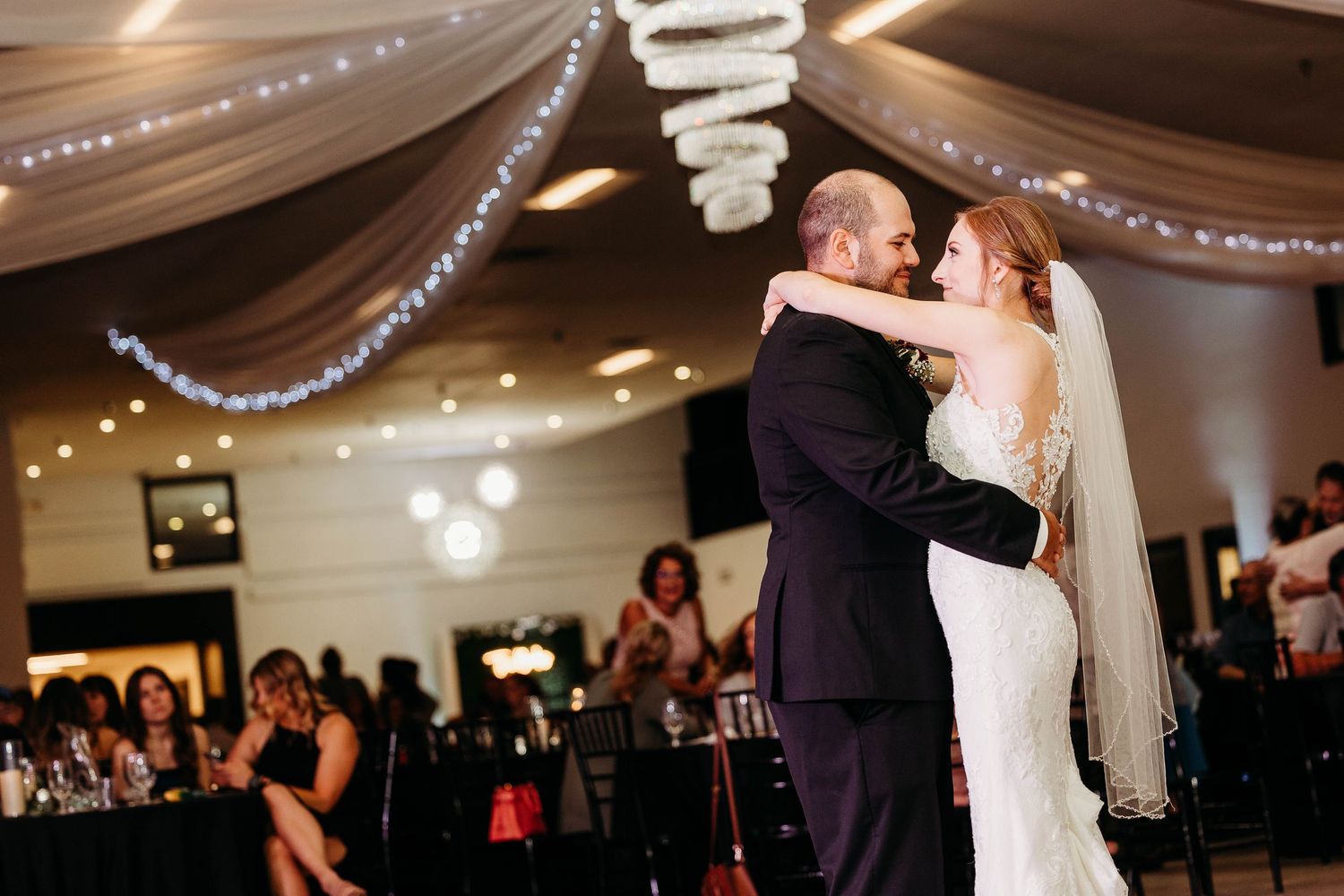 Couples dancing together during a romantic wedding reception under twinkling lights and elegant decor.