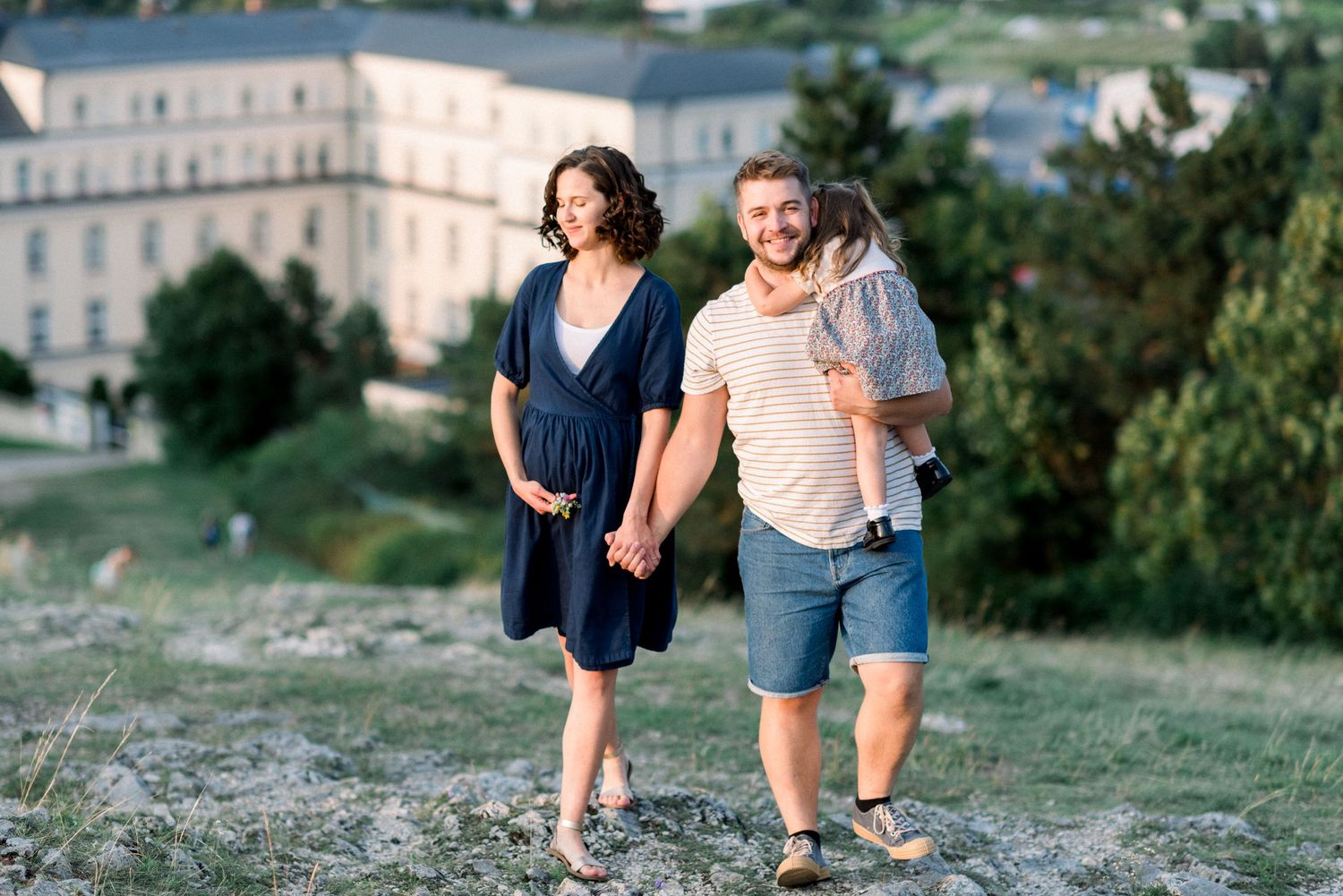 A joyful family moment captured on a hilltop with a scenic city backdrop.
