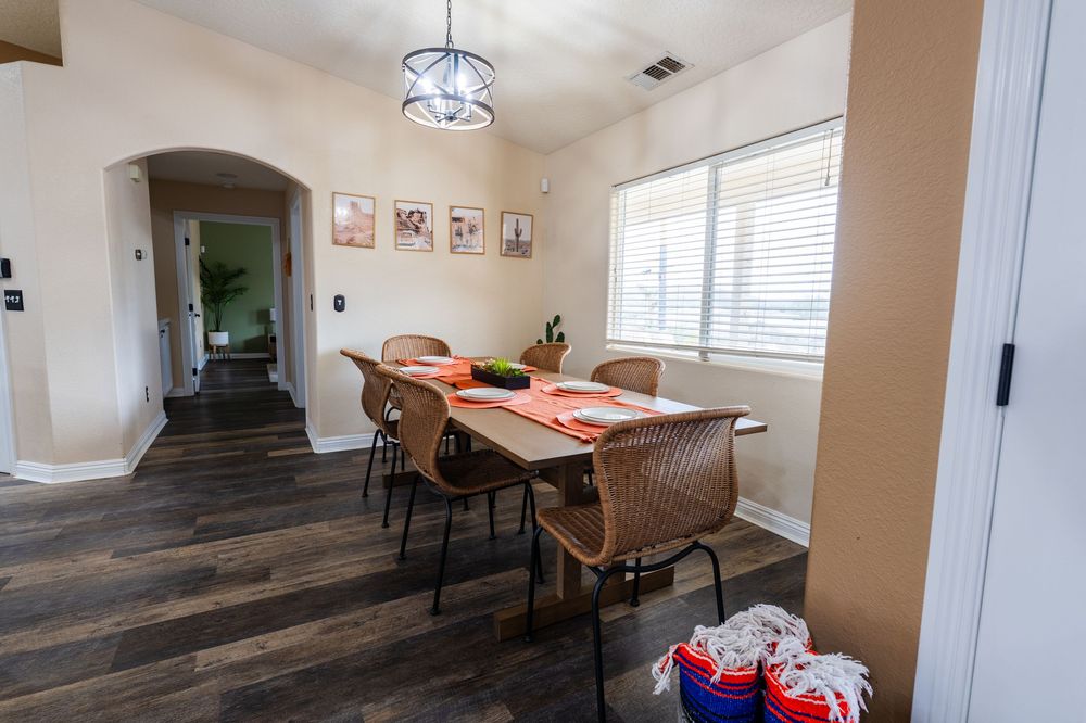 A panoramic view of an empty modern living room with beige walls, hardwood floors and natural lighting.