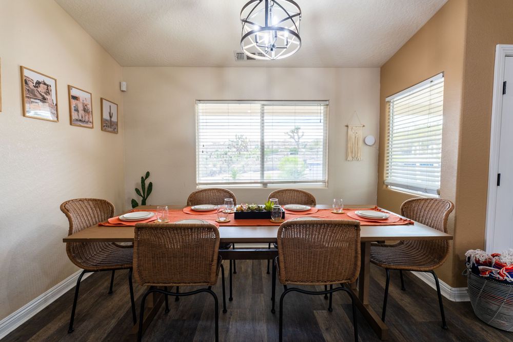 Modern dining room interior with brown chairs and table set against beige walls and window.