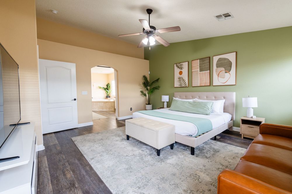 Modern apartment interior featuring carpeted bedroom with green accent wall and ceiling fan.