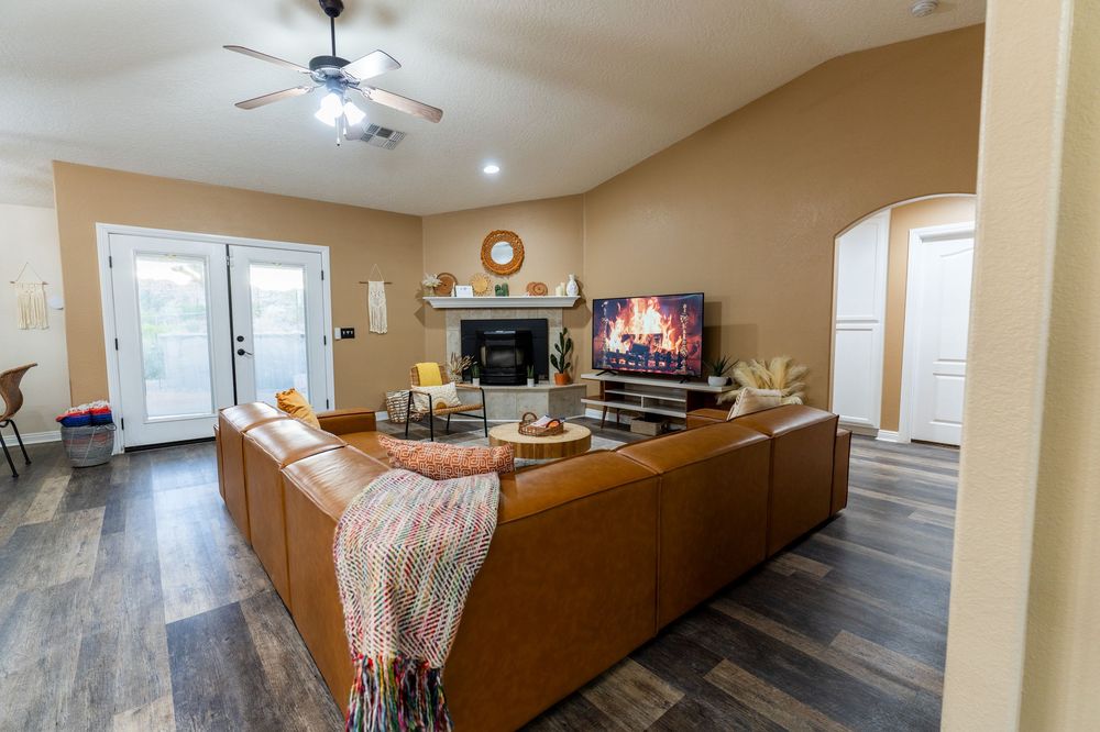 Modern open concept living room and kitchen with grey flooring and beige walls showcases recessed lighting and clean lines.