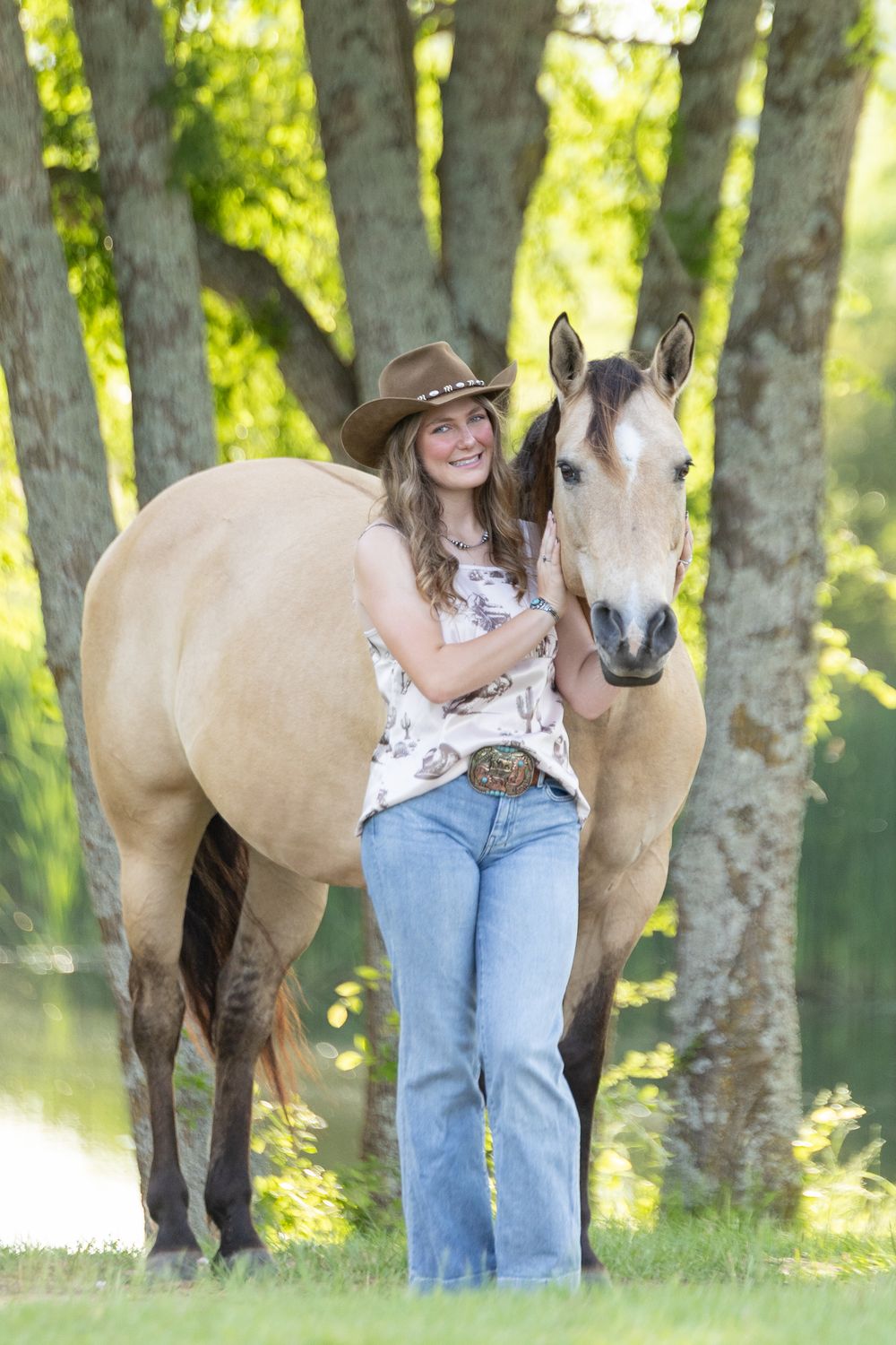 equine senior pictures at sunset, girl standing in front of tree backlit with sunshine