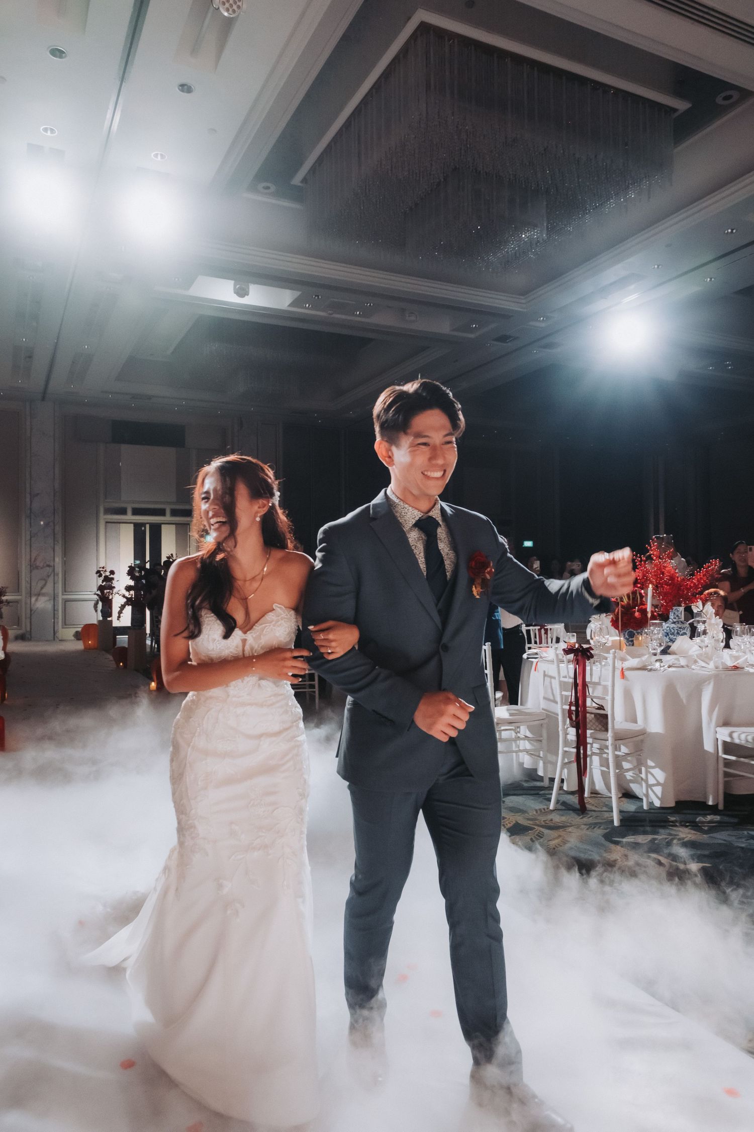 Wedding couple dancing in a fog-filled ballroom with dramatic lighting effects. Singapore