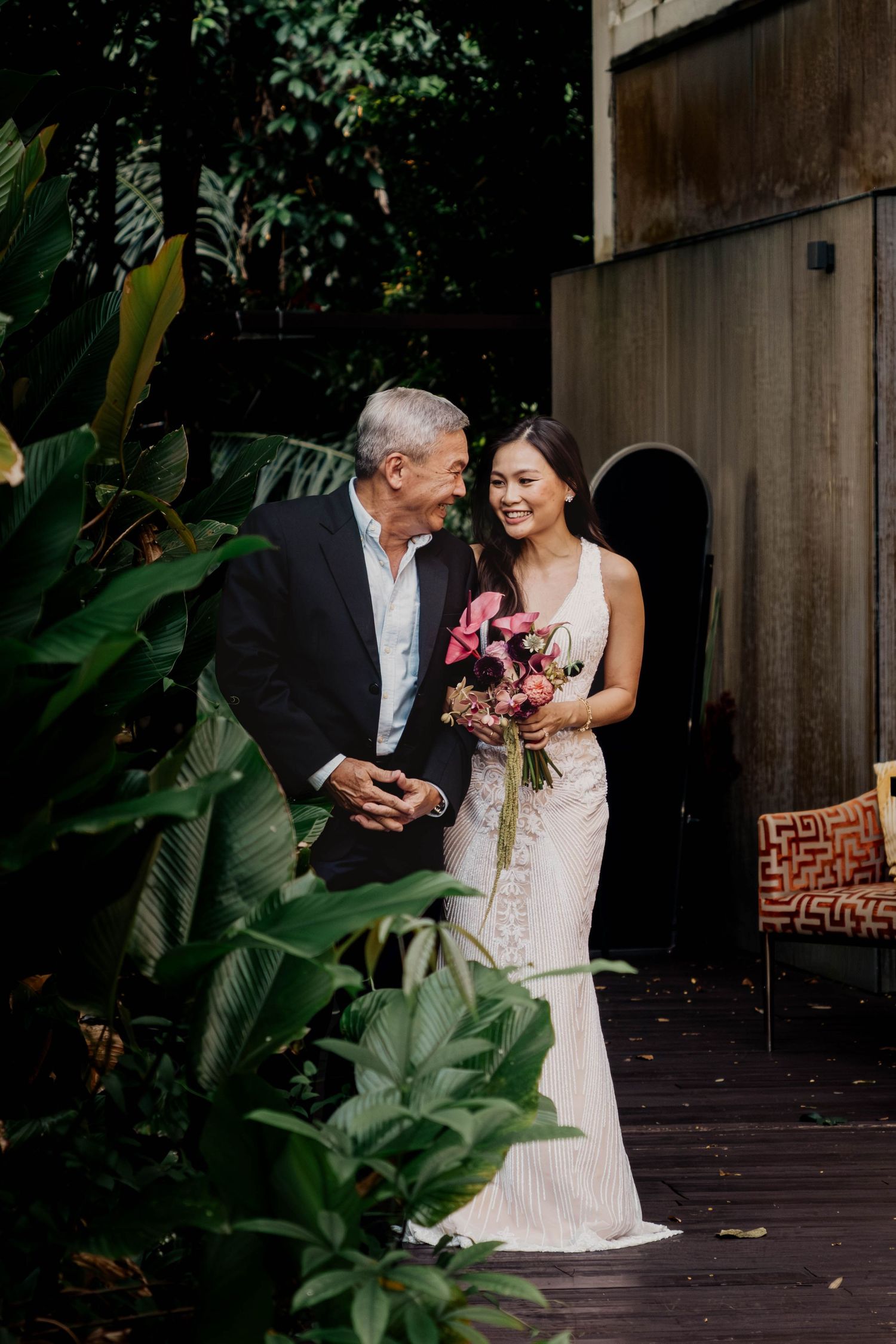 Intimate moment captured on wooden deck surrounded by tropical foliage. Singapore