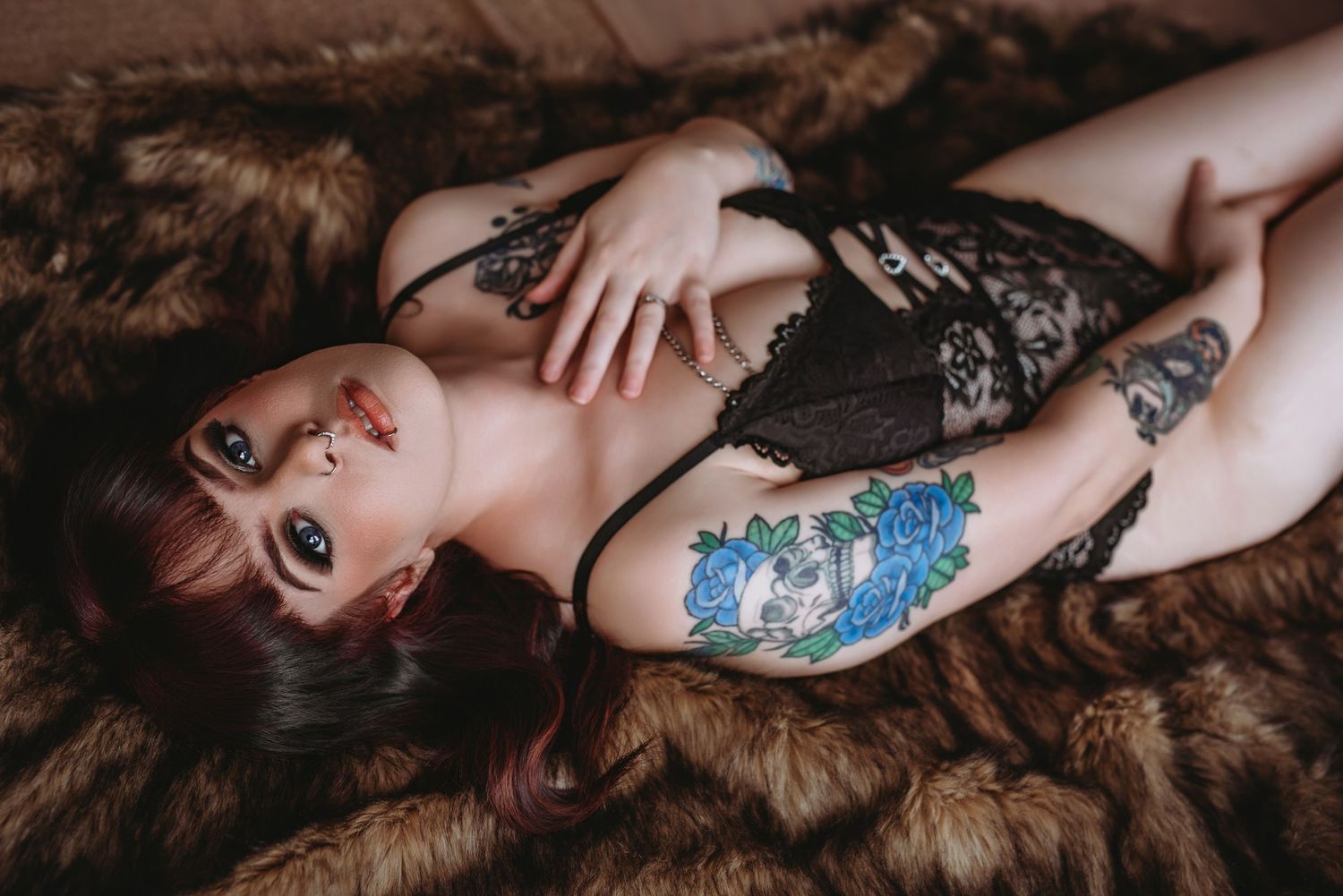 Person lying on bed wearing teal clothing with colorful tattoos on hip and thigh area.