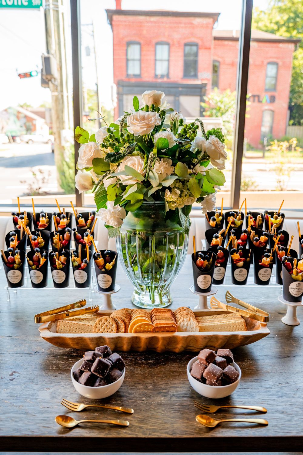 Wedding dessert table with floral centerpiece, chocolate truffles, cookies, and fruit cups.