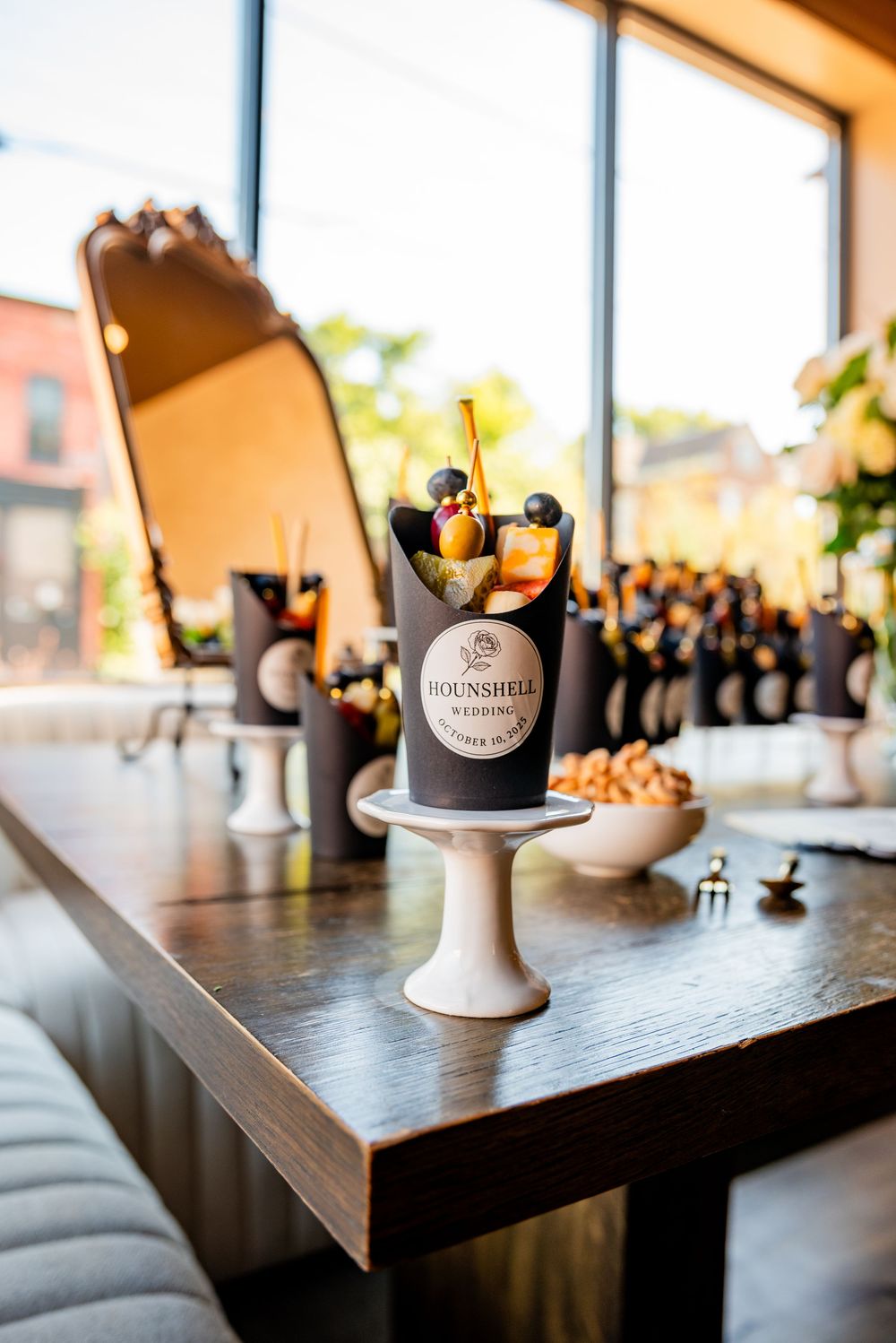 Elegant wedding reception cocktail display with Hounshell branding on a wooden pedestal table.