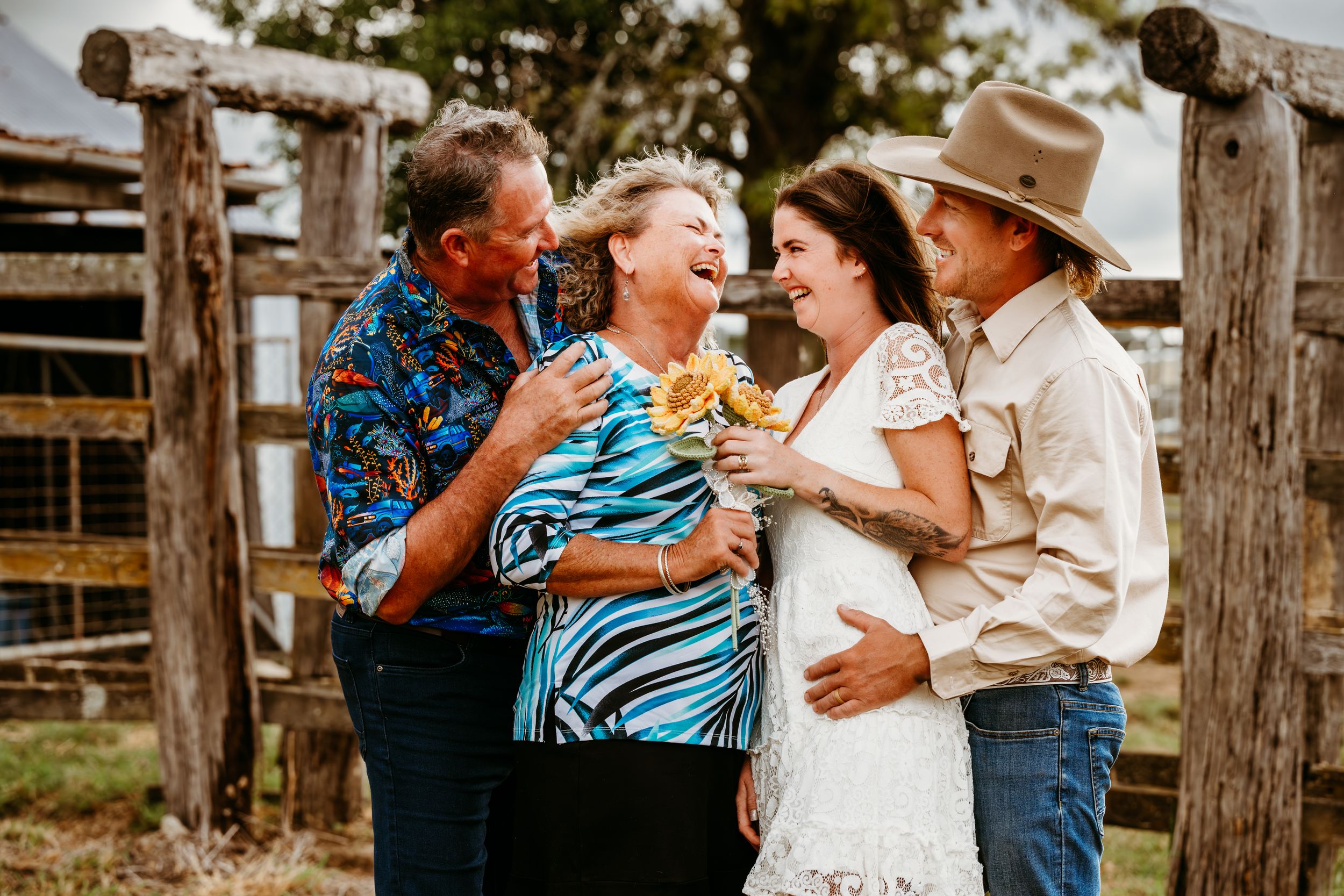 Joyful family laughing together outdoors at a rustic farm wedding celebration.