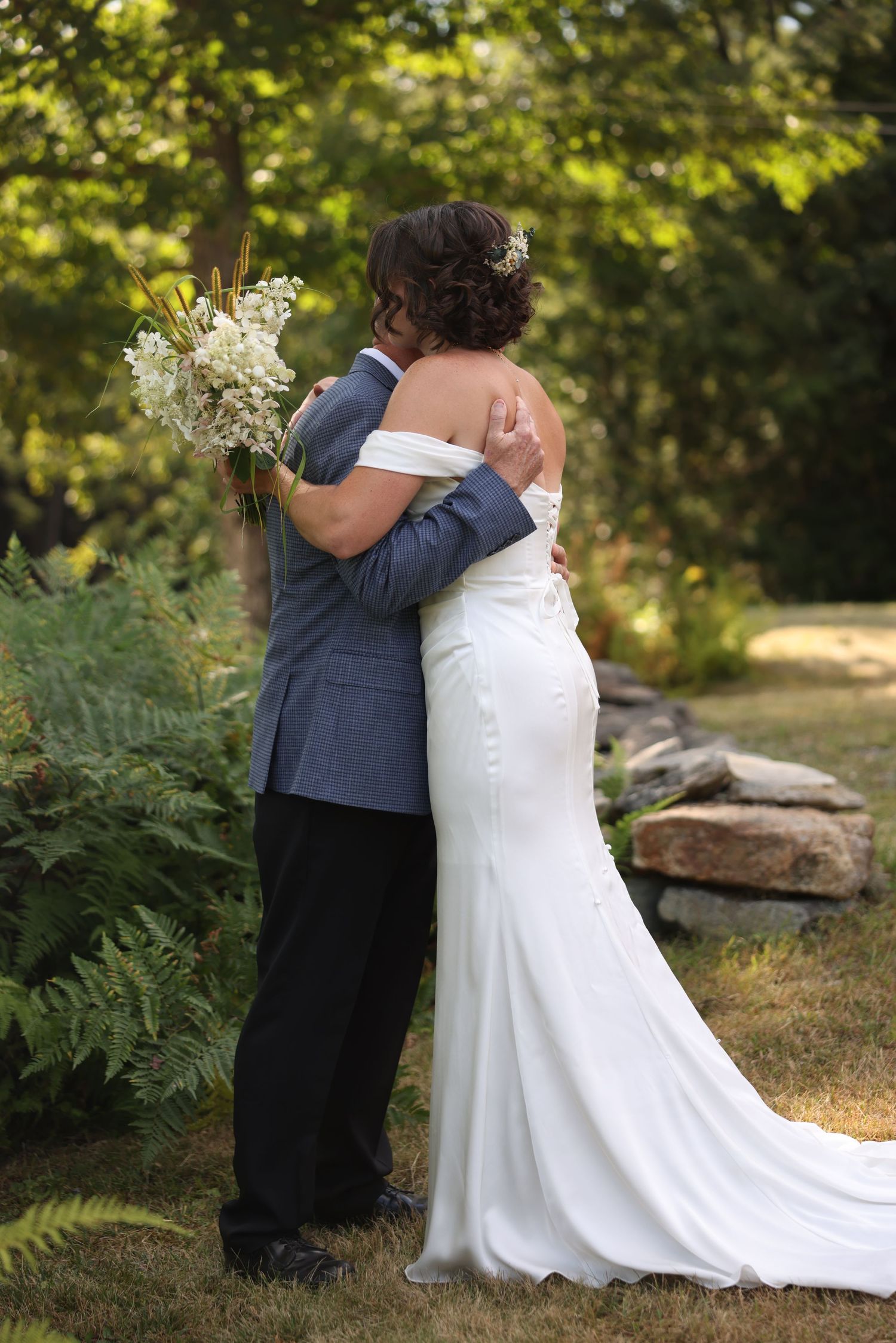 Bride and groom share tender embrace in lush green garden during romantic first look wedding moment.